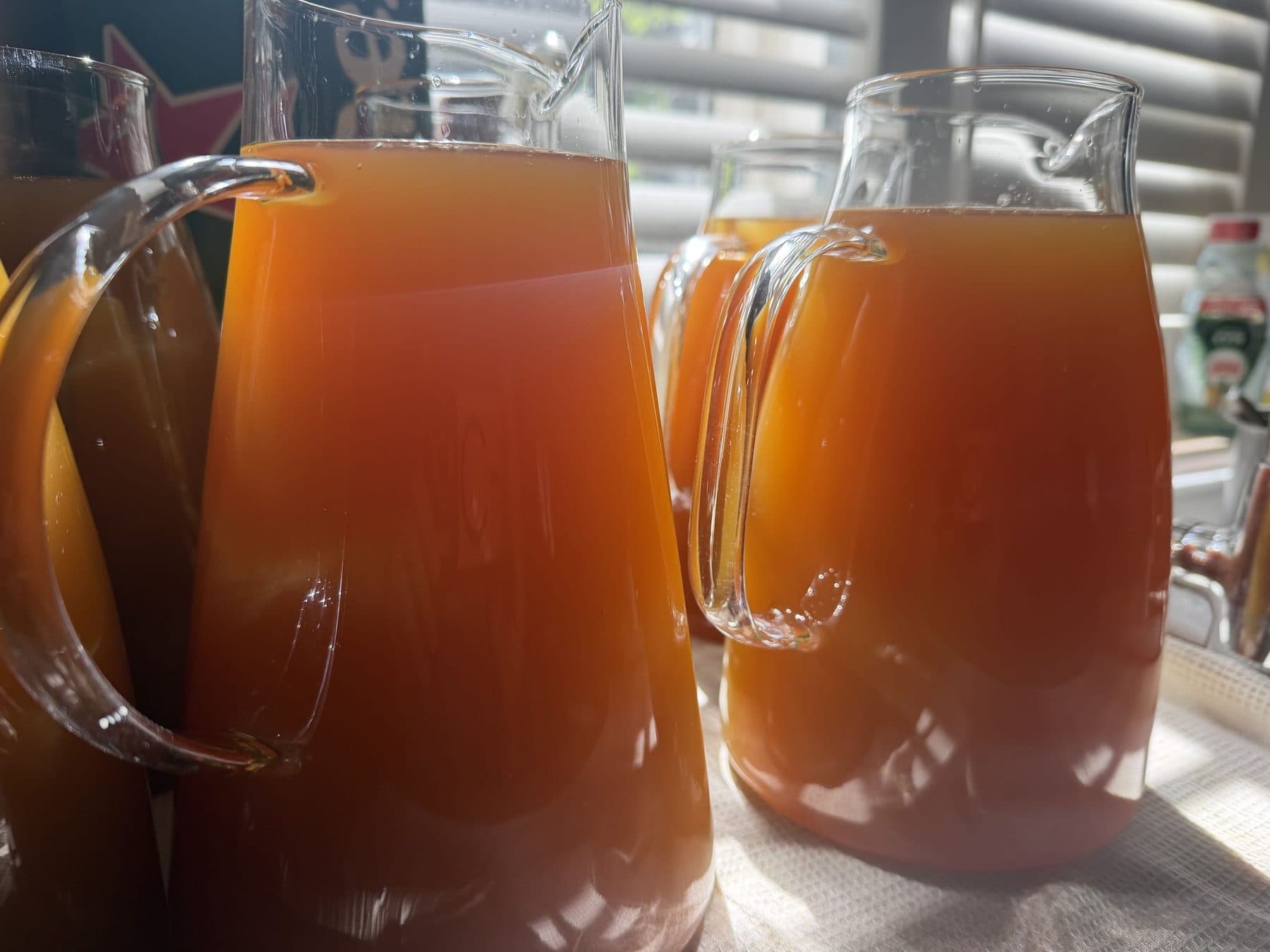 Glass jugs of freshly brewed amber Schniffells cooling in a sunlit window