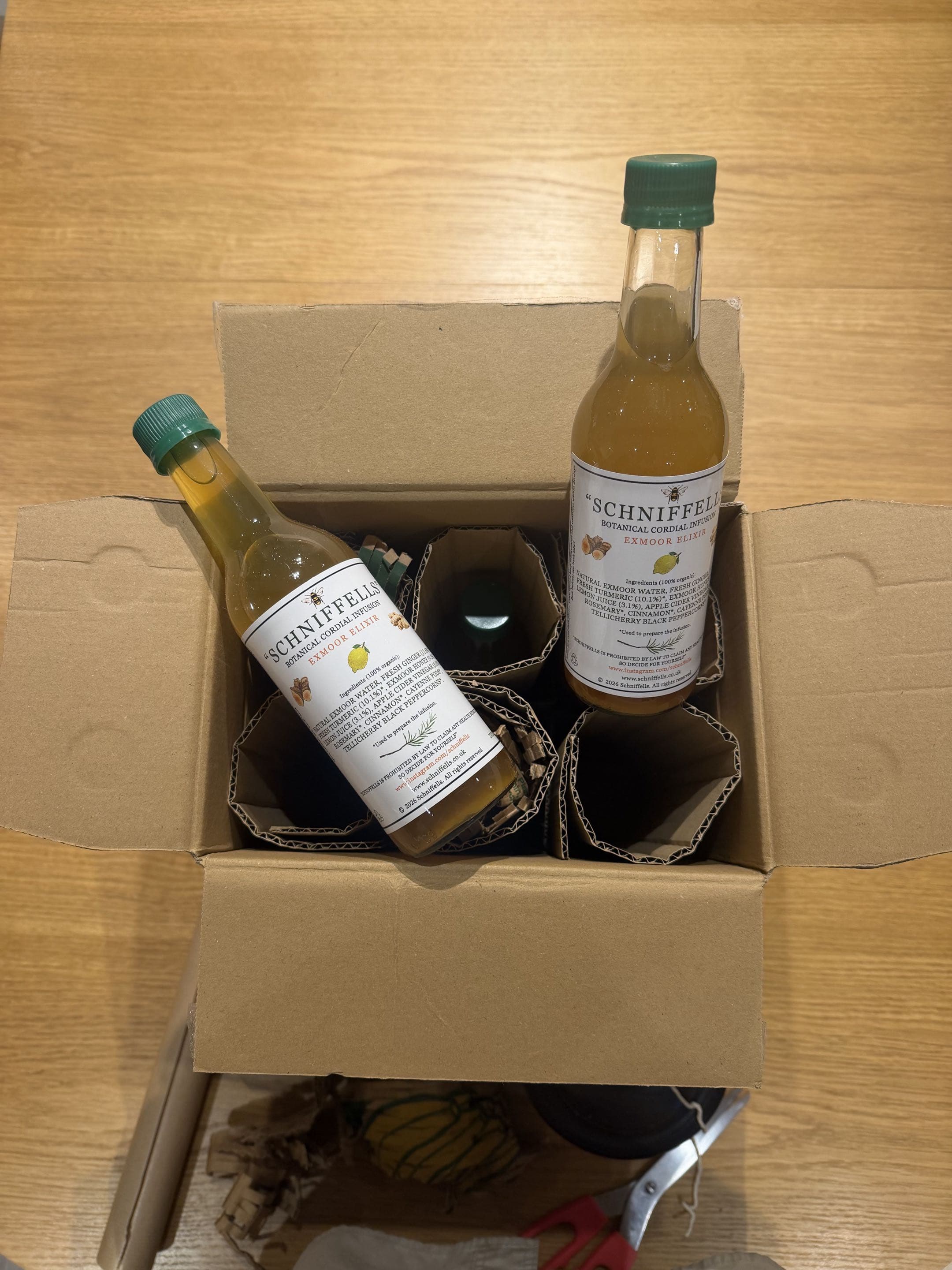 Two Schniffells bottles packed in a reused cardboard box, lid open